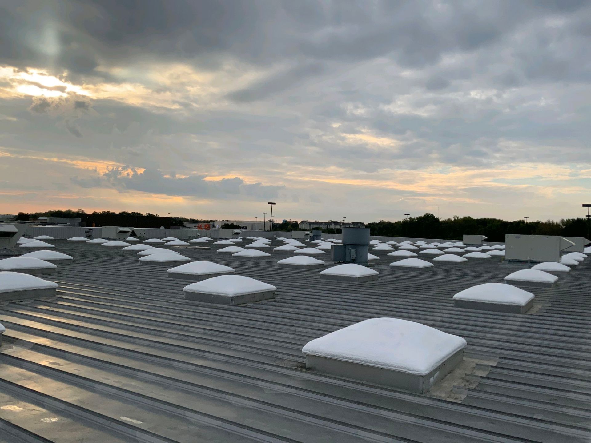 A roof with a lot of skylights on it and a cloudy sky in the background.