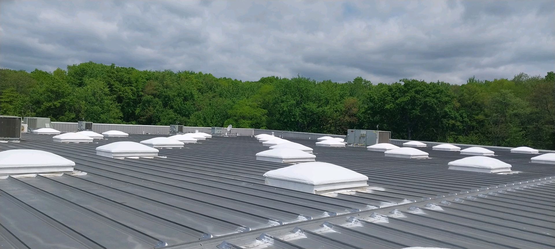 A roof with a lot of snow on it and trees in the background
