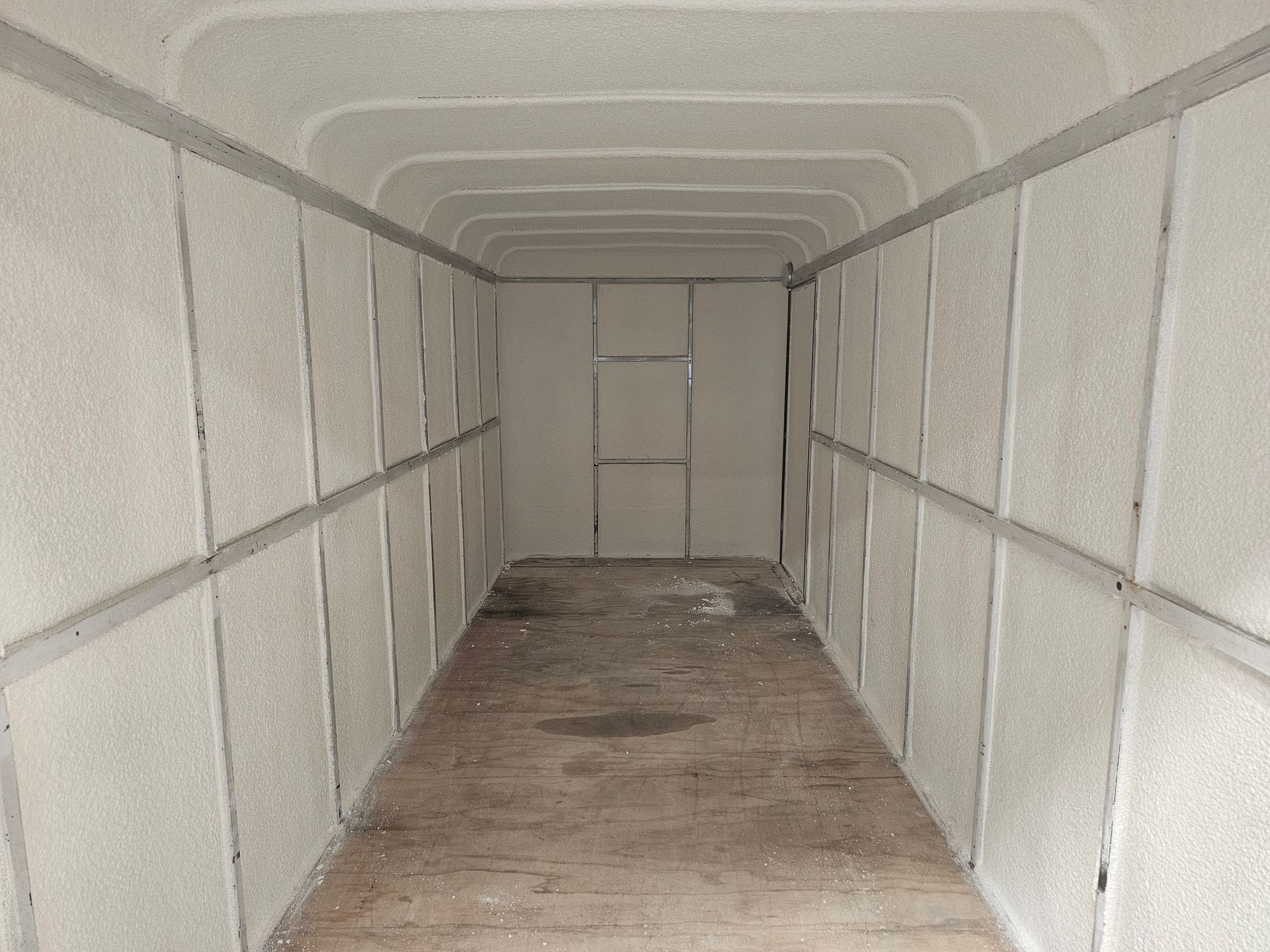 A very long hallway with white walls and a wooden floor