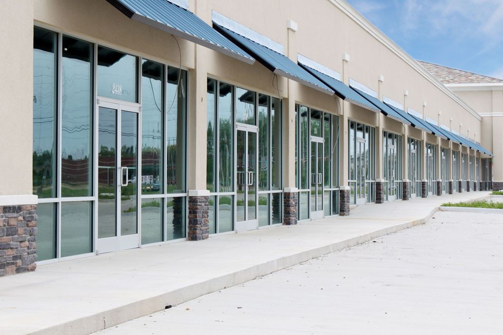 Empty commercial building with large glass windows and awnings.