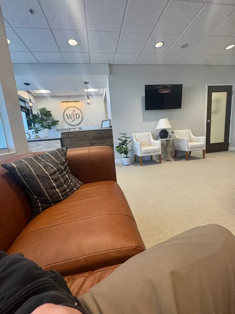 Lobby with brown leather sofa, white chairs, and a reception desk.