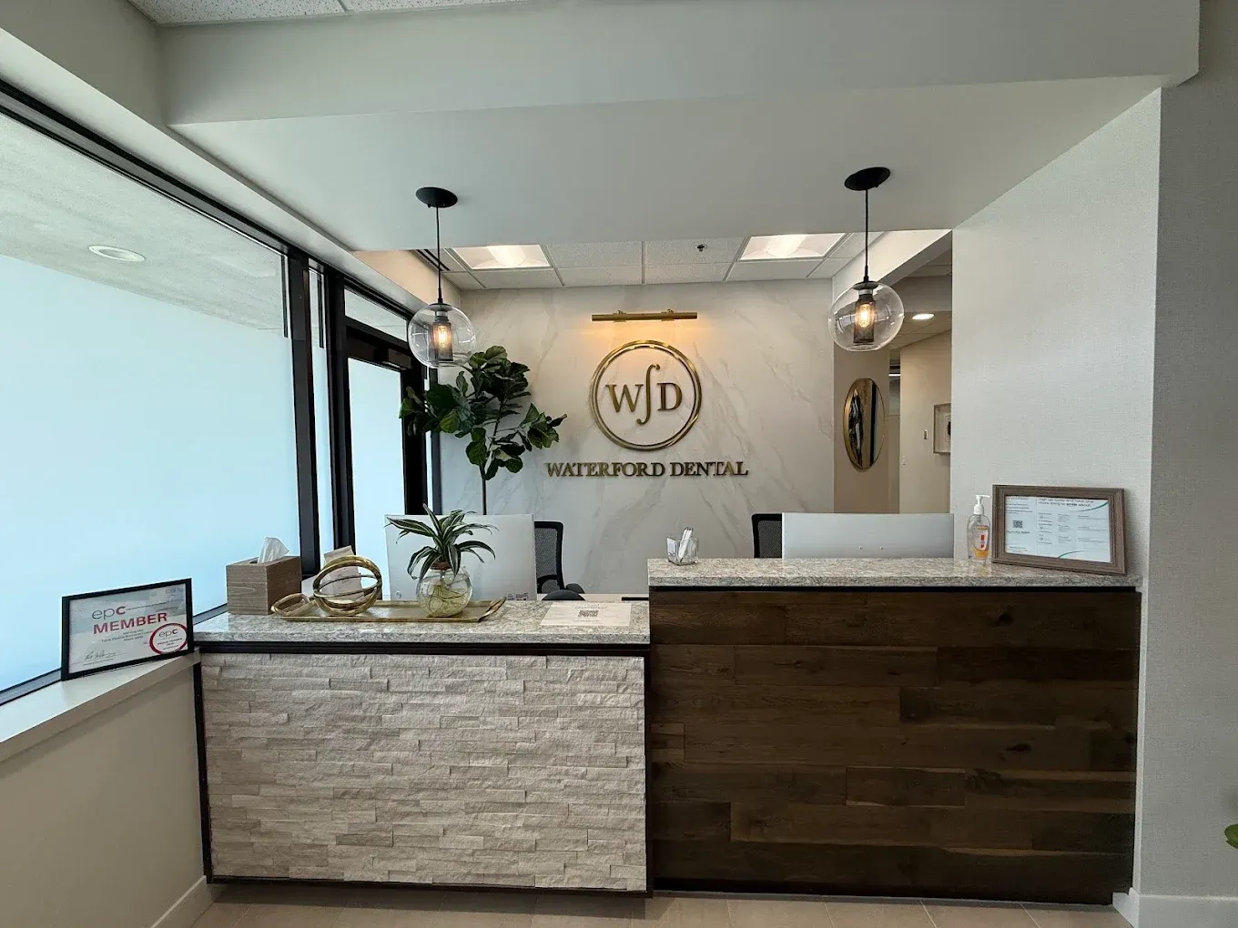 Reception desk at Waterford Dental with logo, plants, and modern decor.