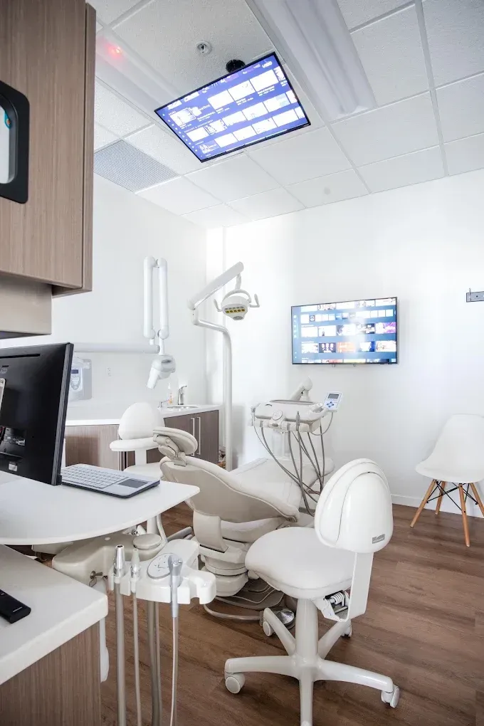 Dental office interior, featuring a dental chair, equipment, a monitor, and cabinetry.