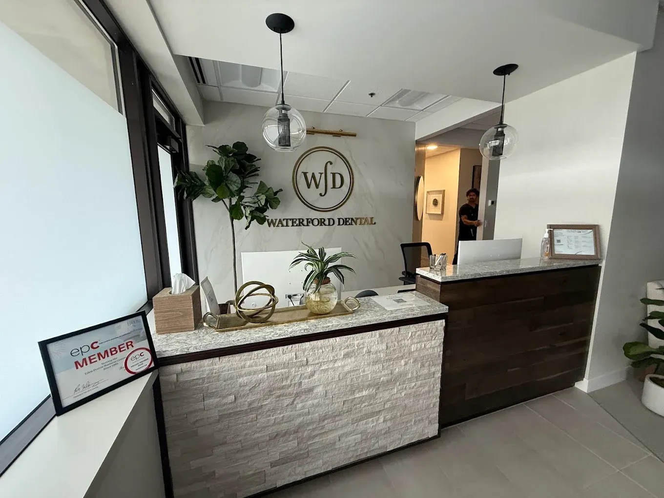 Reception desk with logo (WJD) in an office setting. Front desk has textured stone and wood.