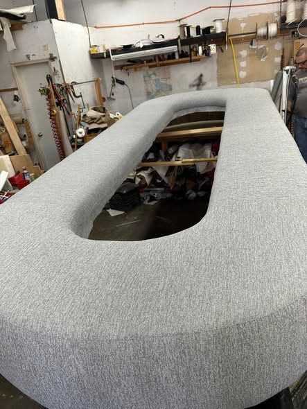 Light gray, U-shaped upholstered table in a workshop setting.