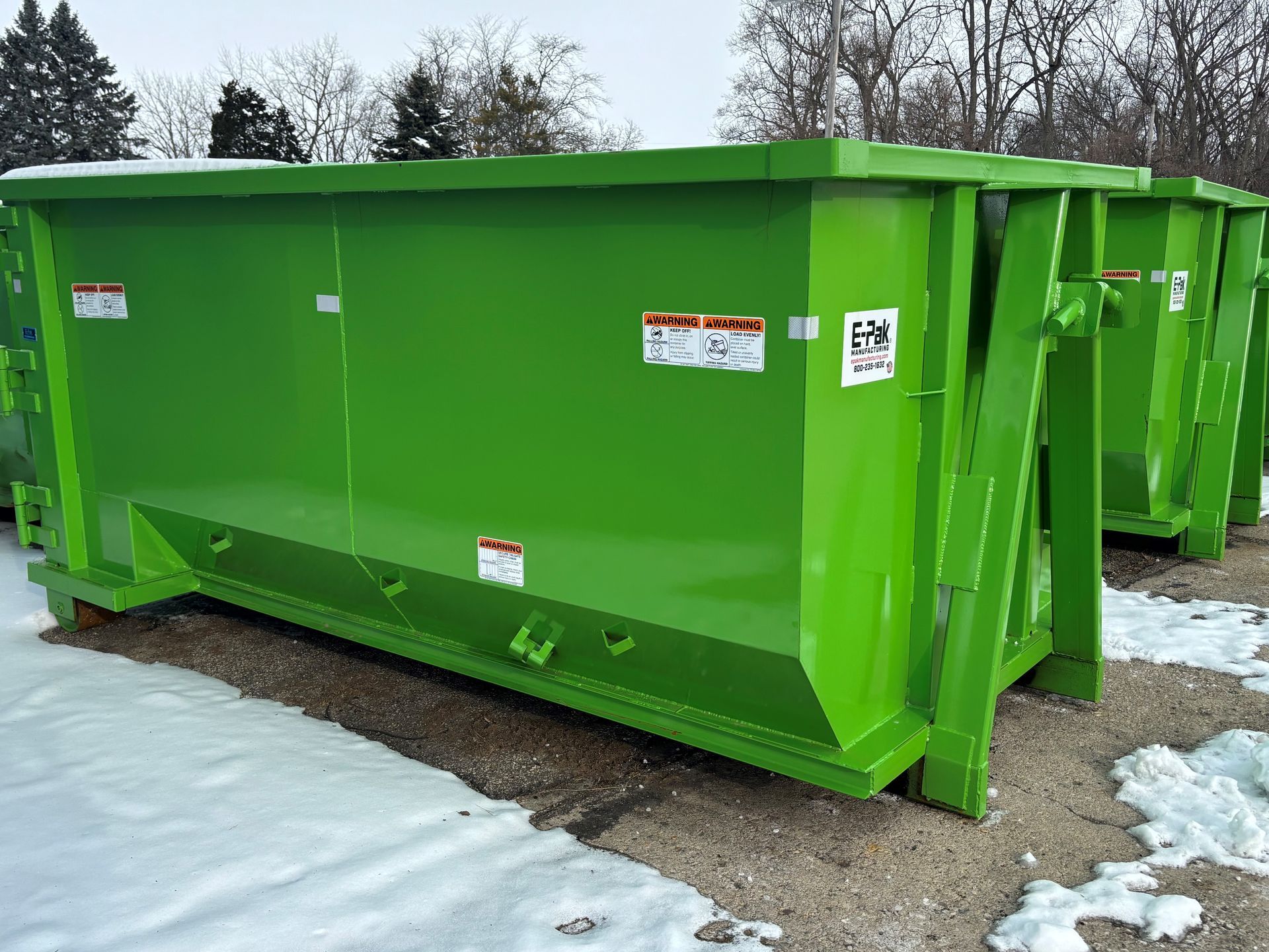 Green industrial dumpster outdoors with snow.