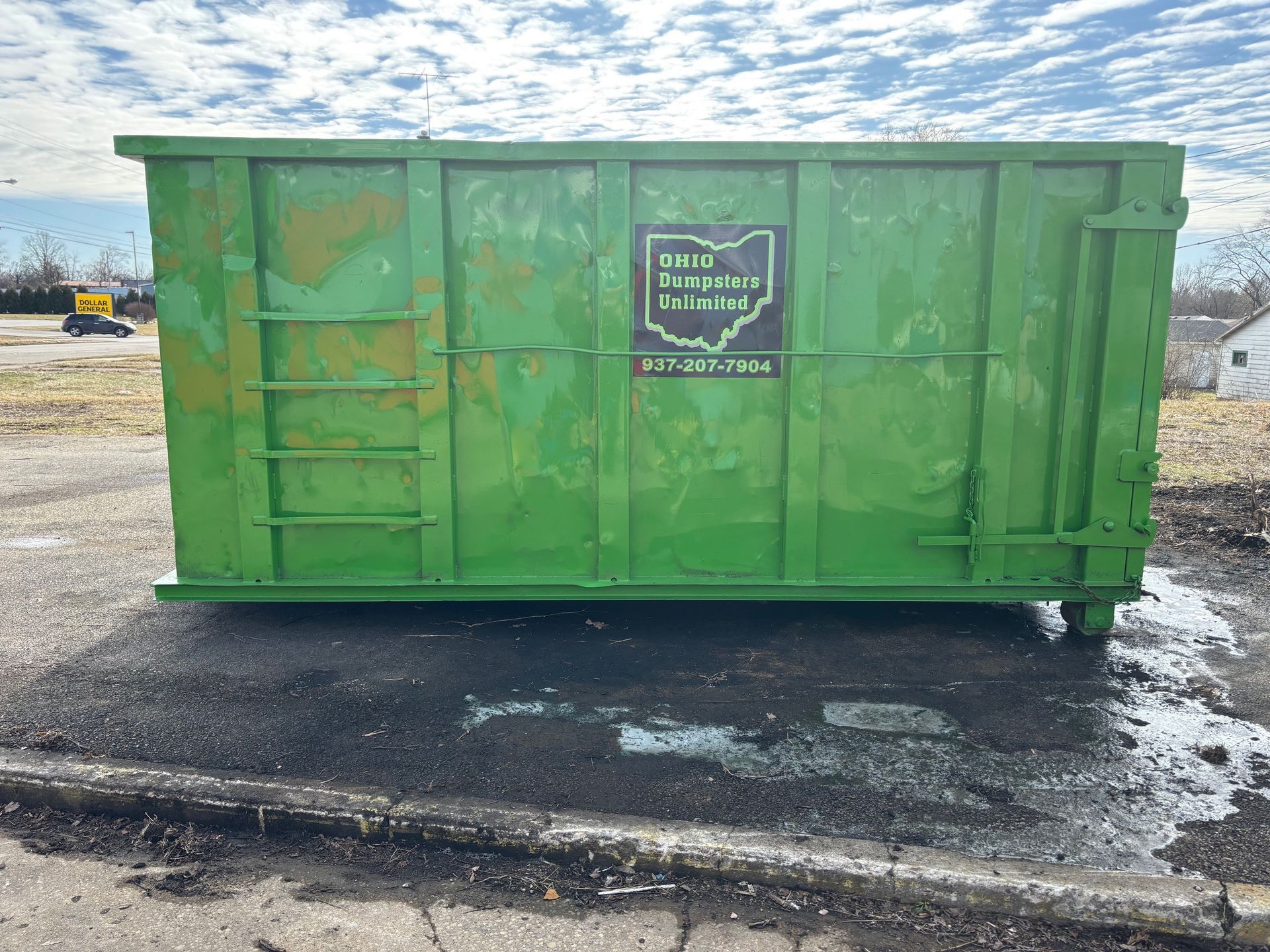Green dumpster on asphalt, with Ohio company logo.