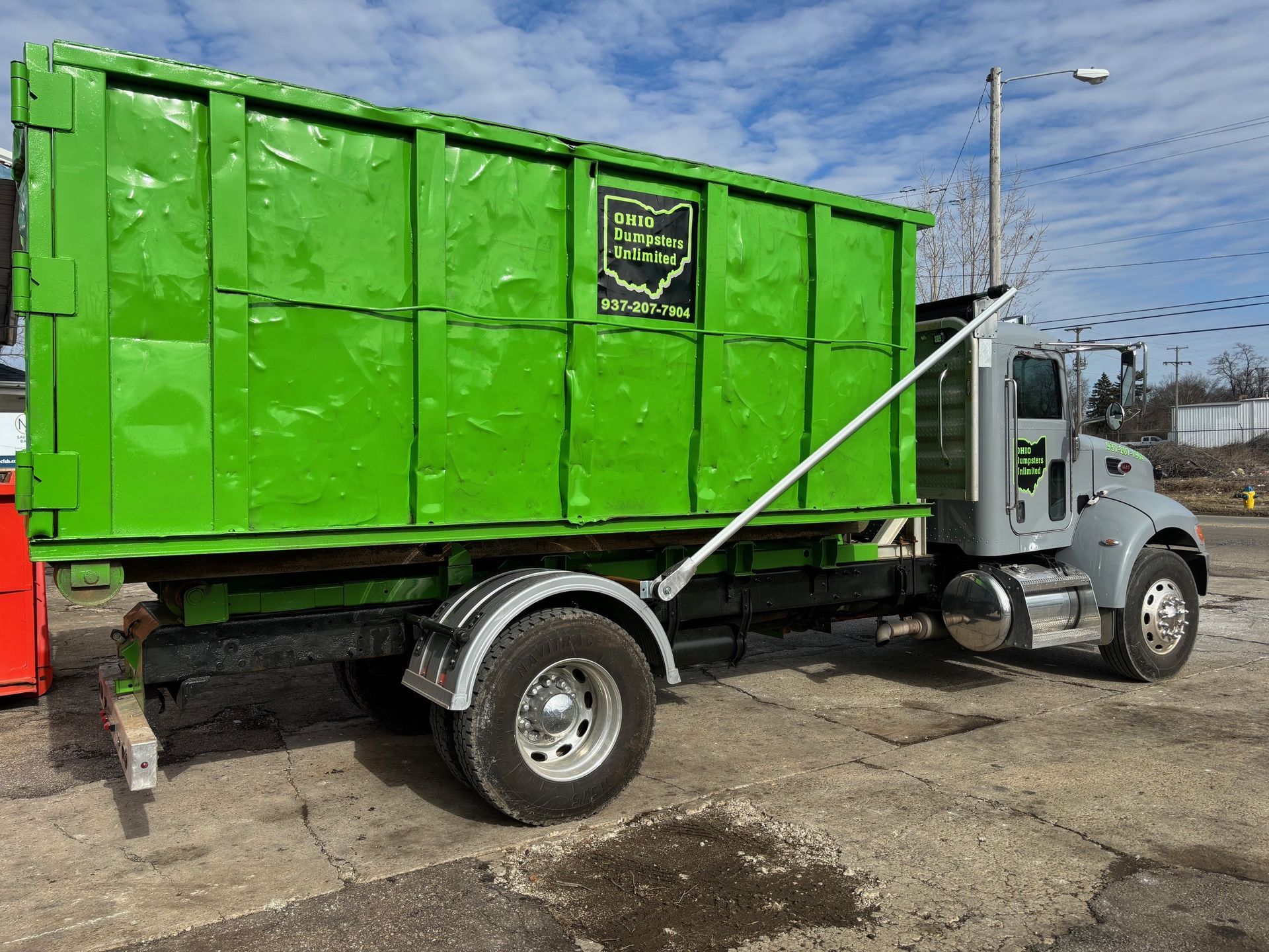 Green dumpster truck in an urban setting.