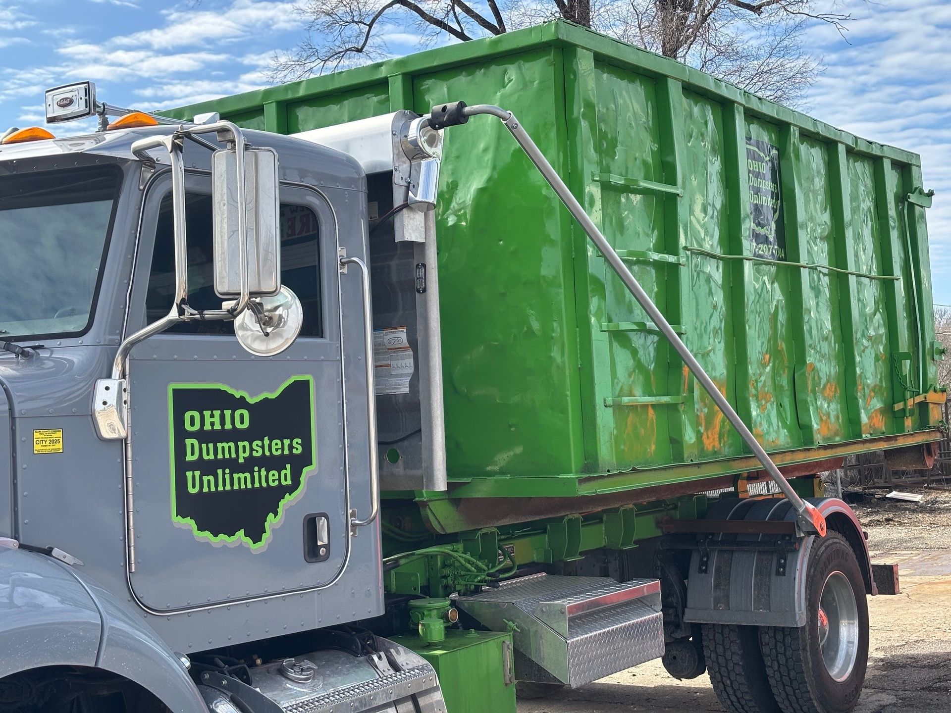 Green dumpster on a gray Ohio Dumpsters Unlimited truck.