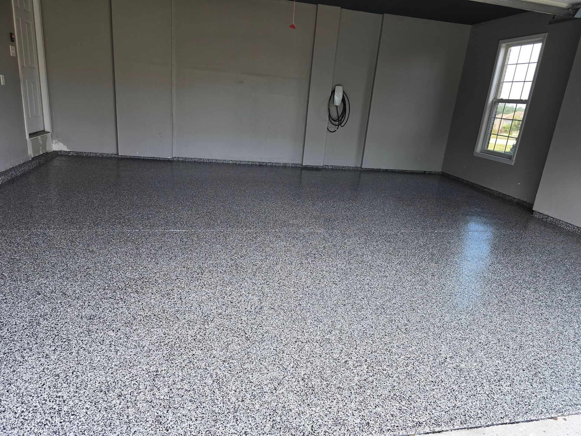 Garage interior with a gray speckled epoxy floor, gray walls, and a window.