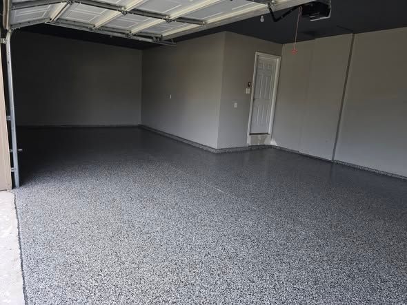 Empty garage interior with a gray speckled epoxy floor and gray walls.