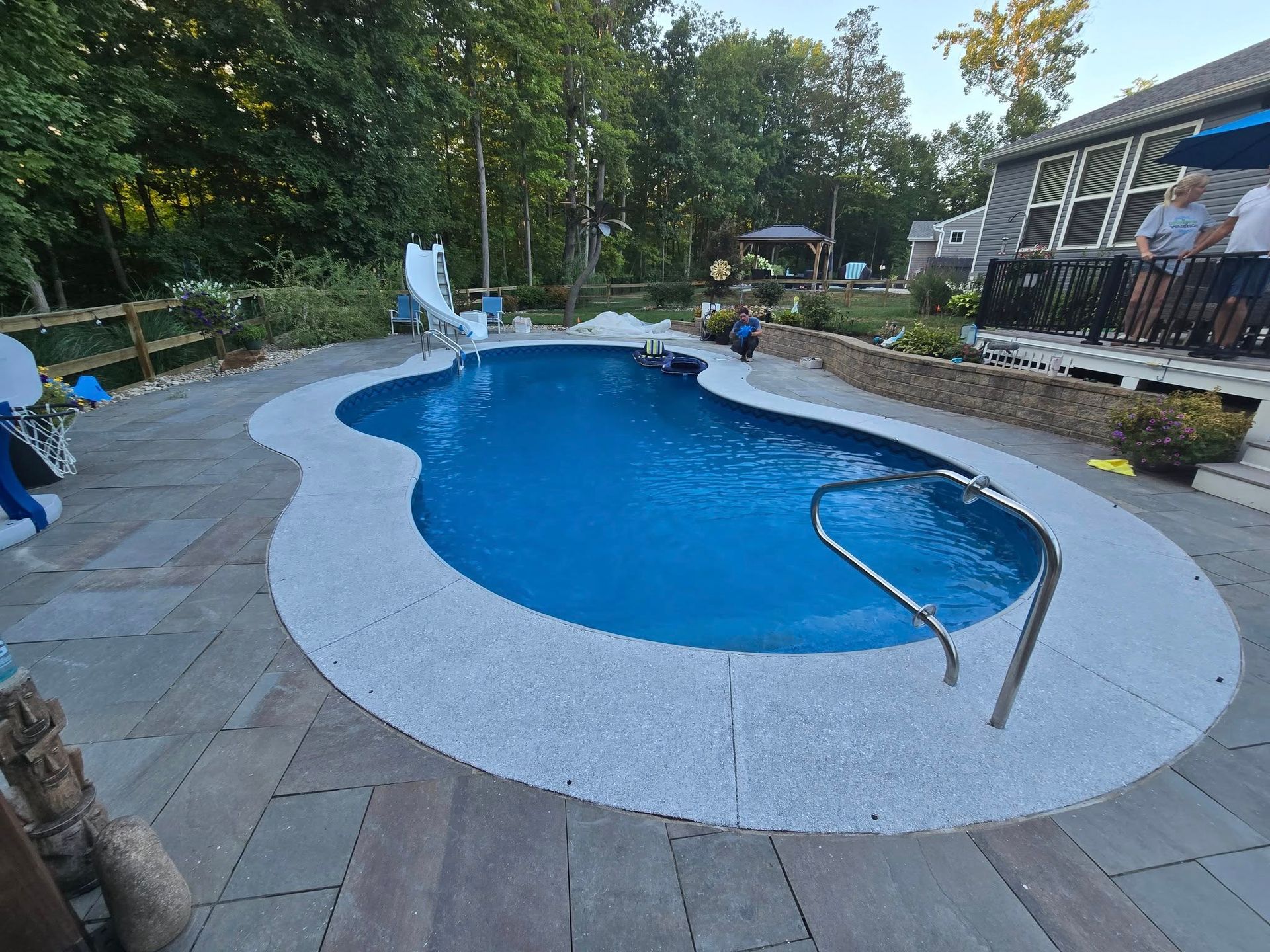 Pool with blue water and white coping surrounded by stone patio.