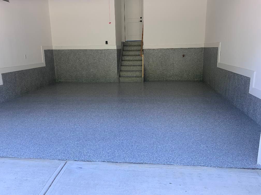 Garage with a gray speckled floor and matching wainscoting, white walls.