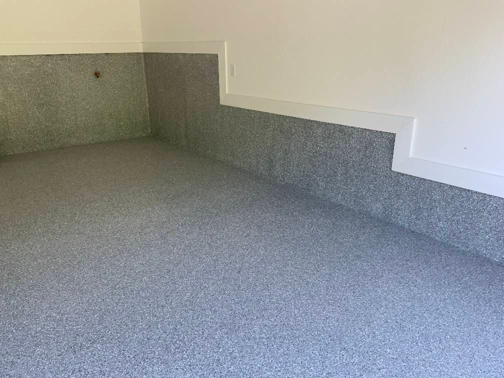 Gray speckled epoxy floor and baseboard in a garage. White walls above.