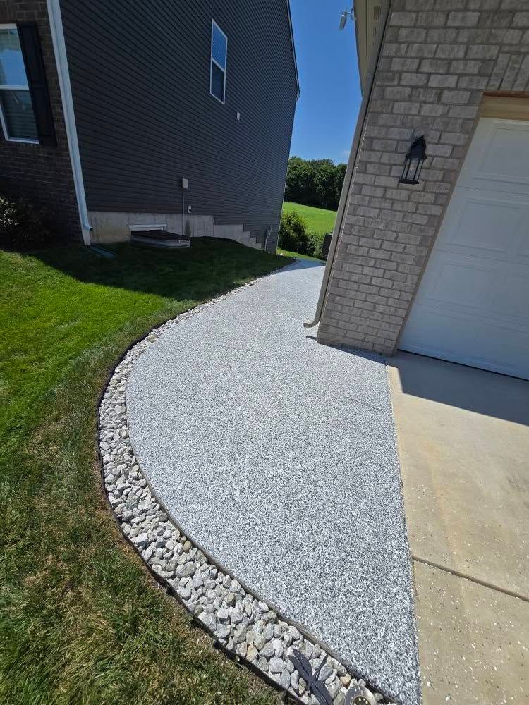 Gravel pathway with rock border beside a green lawn, leading to a garage entrance.