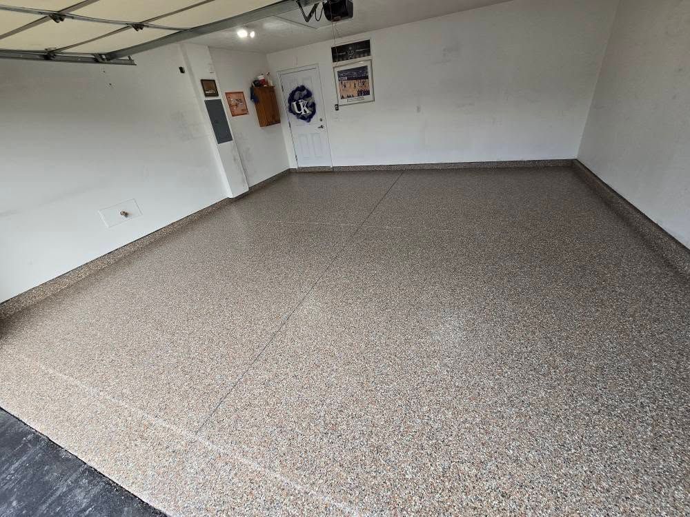 Empty garage with epoxy floor, white walls, and a closed garage door.