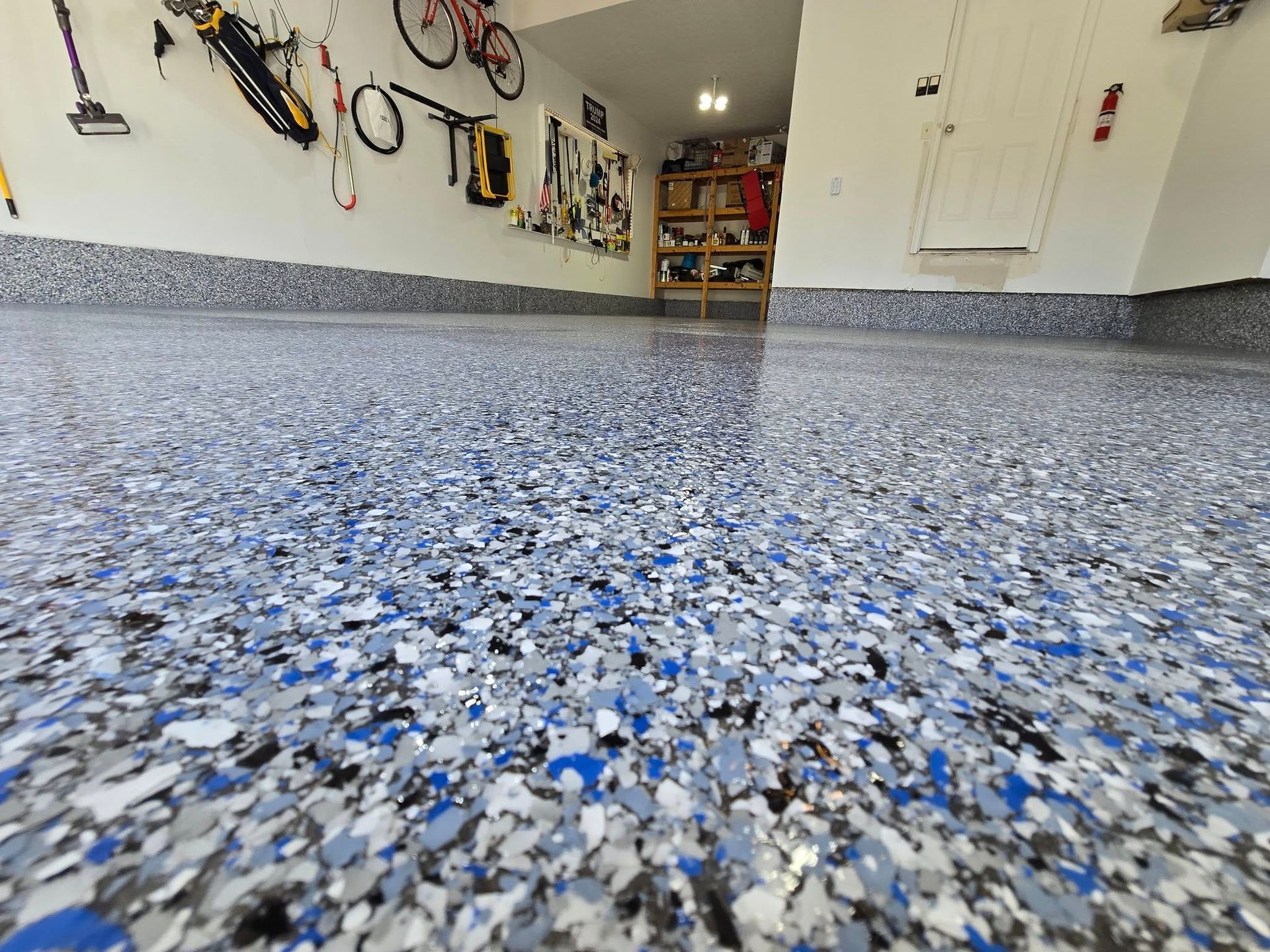 Blue and gray speckled epoxy garage floor. Tools and bikes on wall.