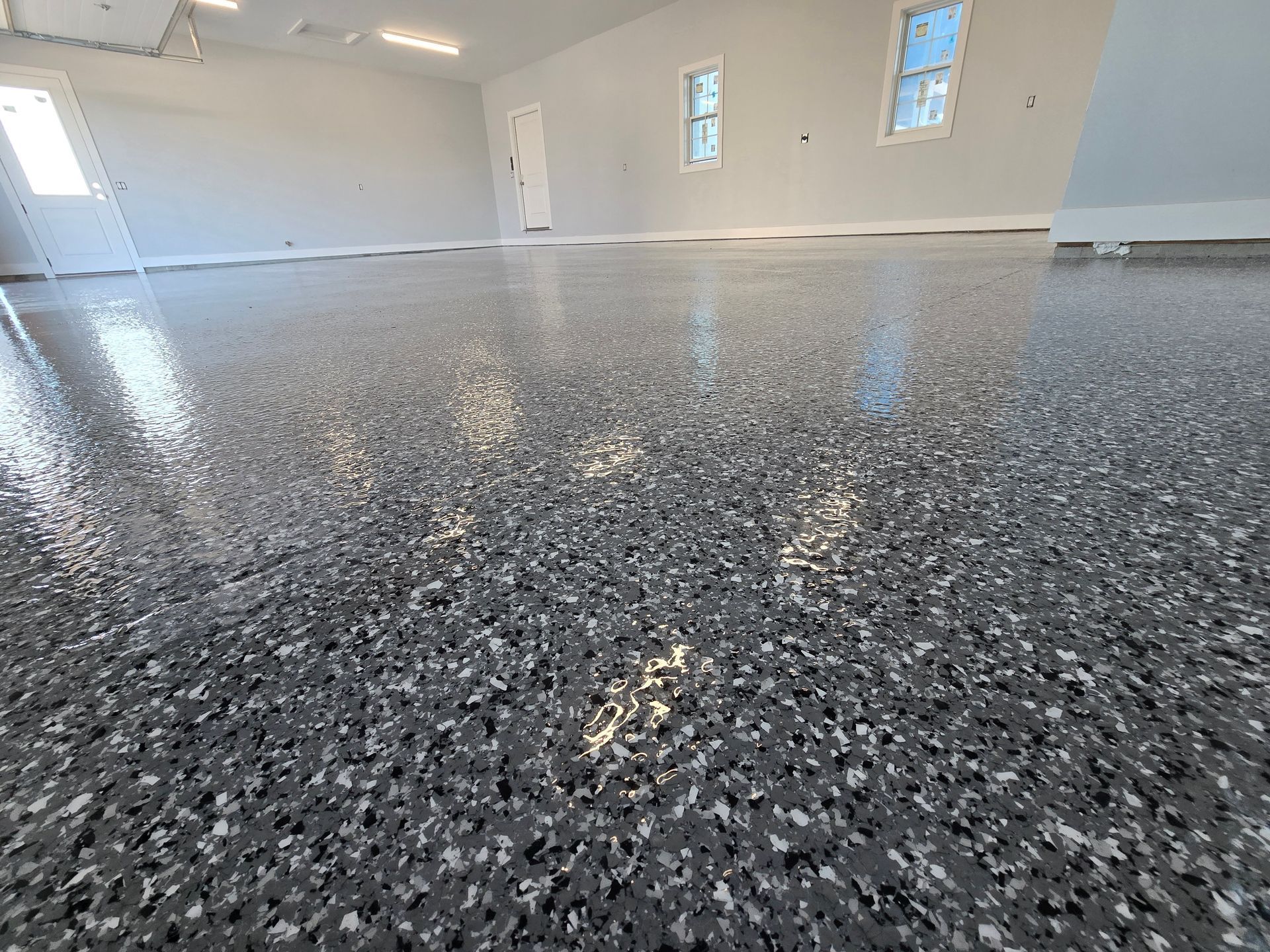 Shiny, speckled epoxy garage floor, light gray and black flecks, reflective finish.