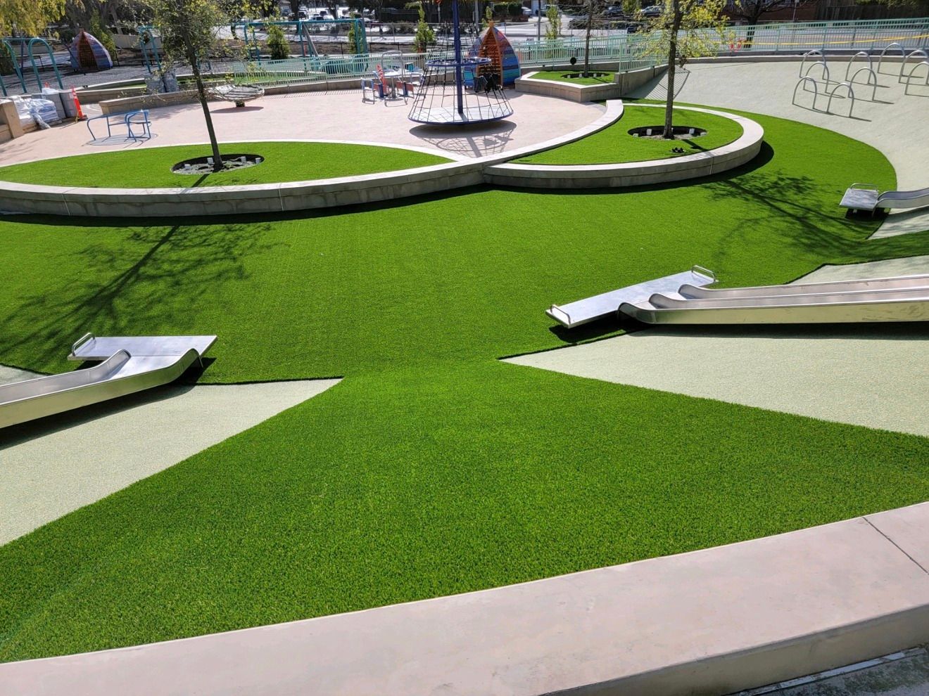 Playground with green artificial turf, landscaping, and play structures.