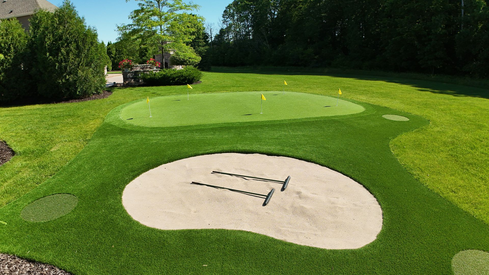 Golf green and sand trap in a manicured lawn.  Green grass, sand, and golf flags are visible.