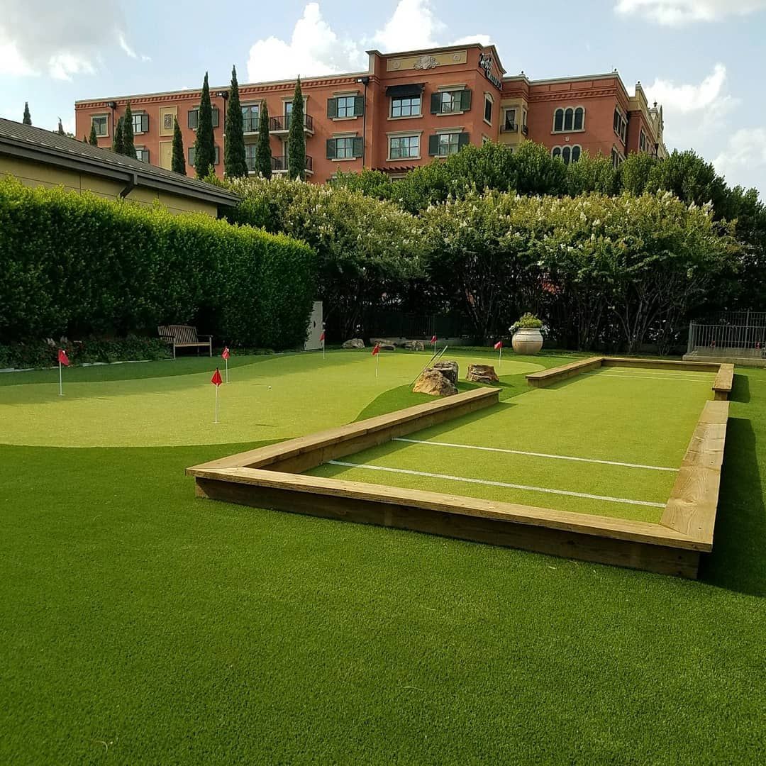 Miniature golf course with a multi-story building in the background on a sunny day.