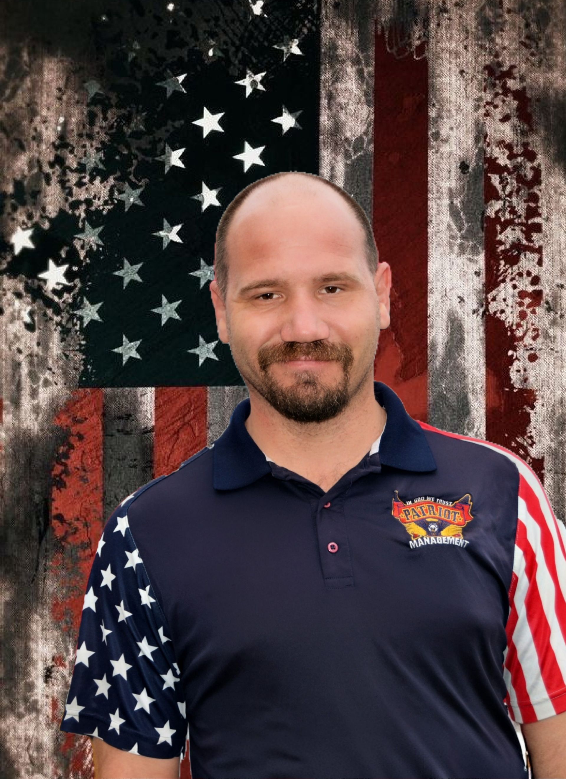 A person with a beard stands before a backdrop of a distressed American flag, wearing a stars and stripes polo shirt.