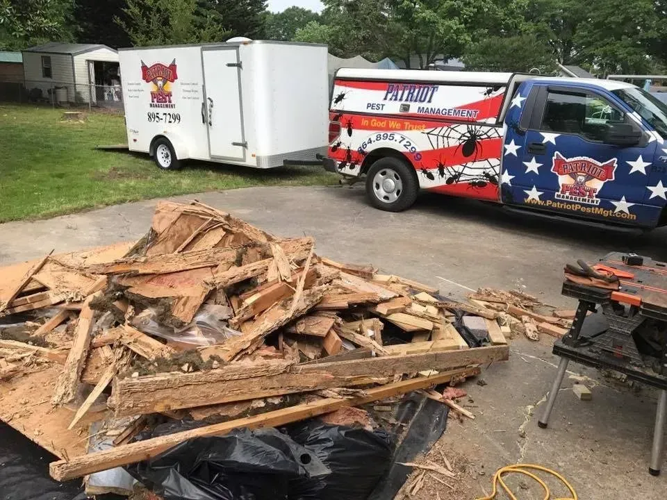Debris pile in front of a work truck and trailer; truck has company logo.