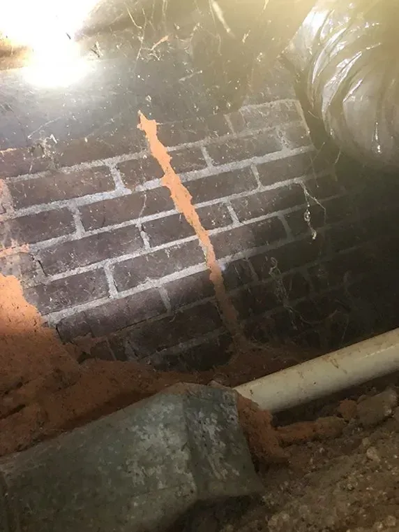 Brick wall with orange termite trail; debris and ductwork in the foreground.
