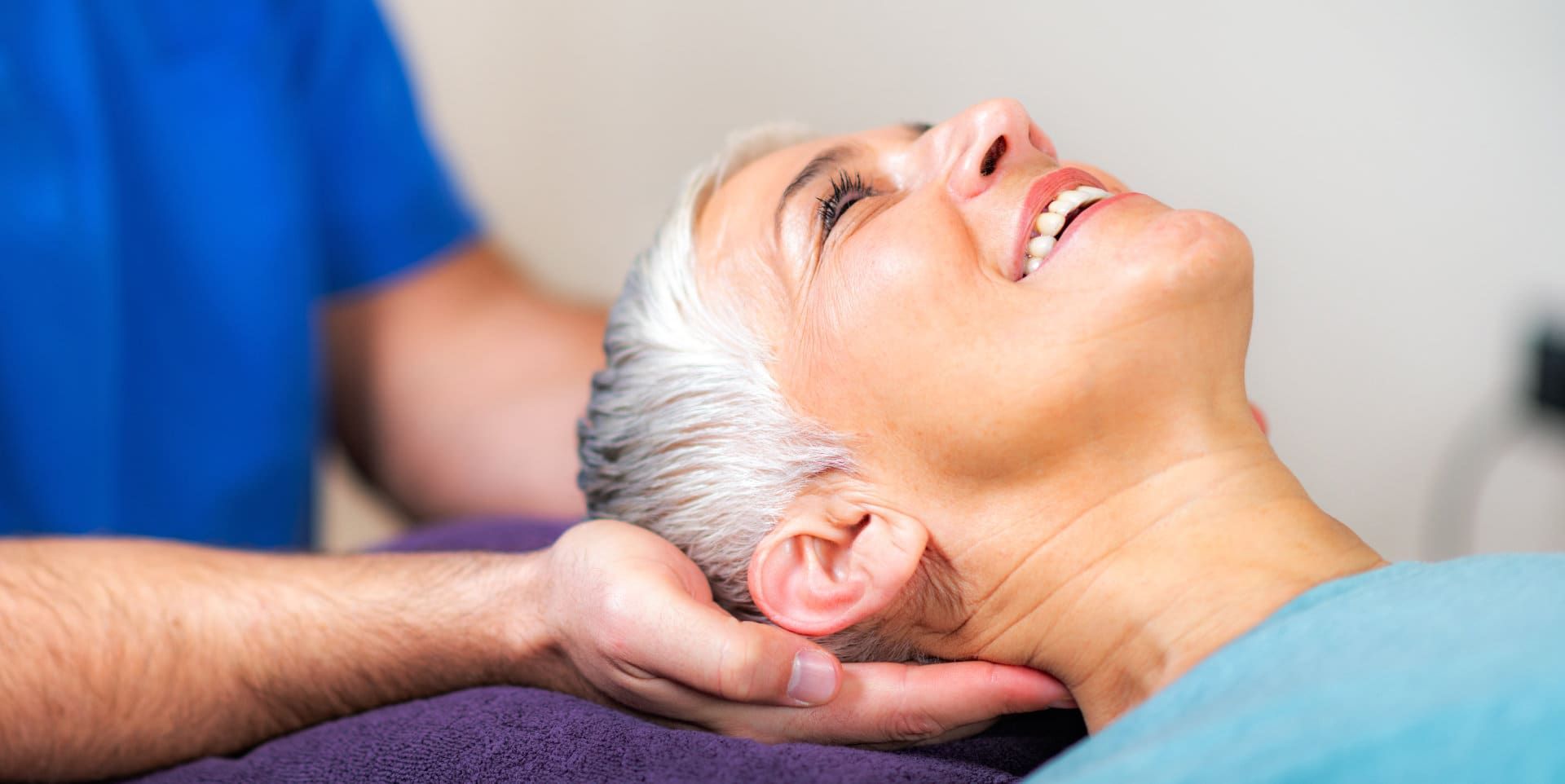 Woman receiving a neck massage from a therapist in a blue shirt