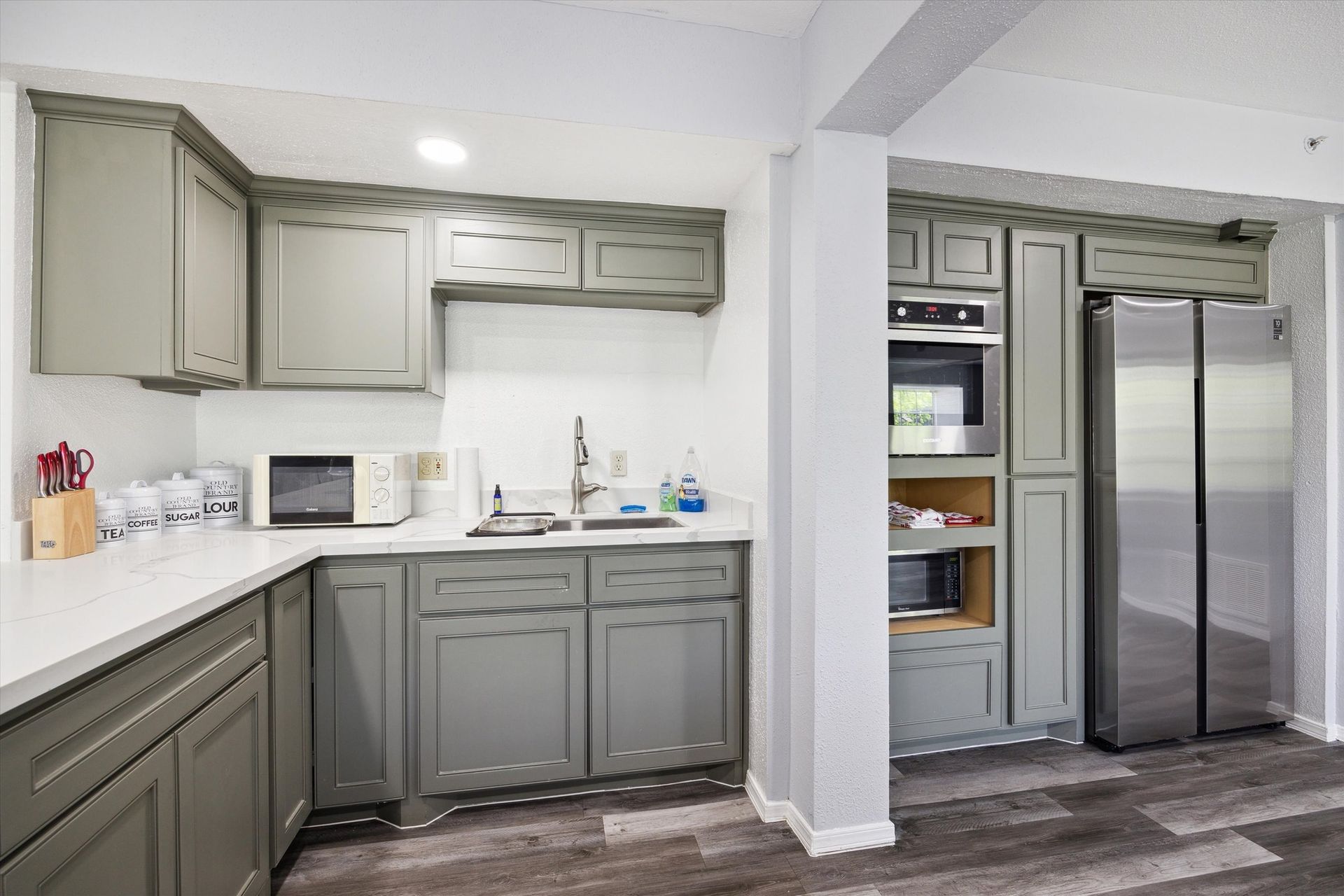 Gray kitchen with cabinets, microwave, oven, refrigerator, and sink.