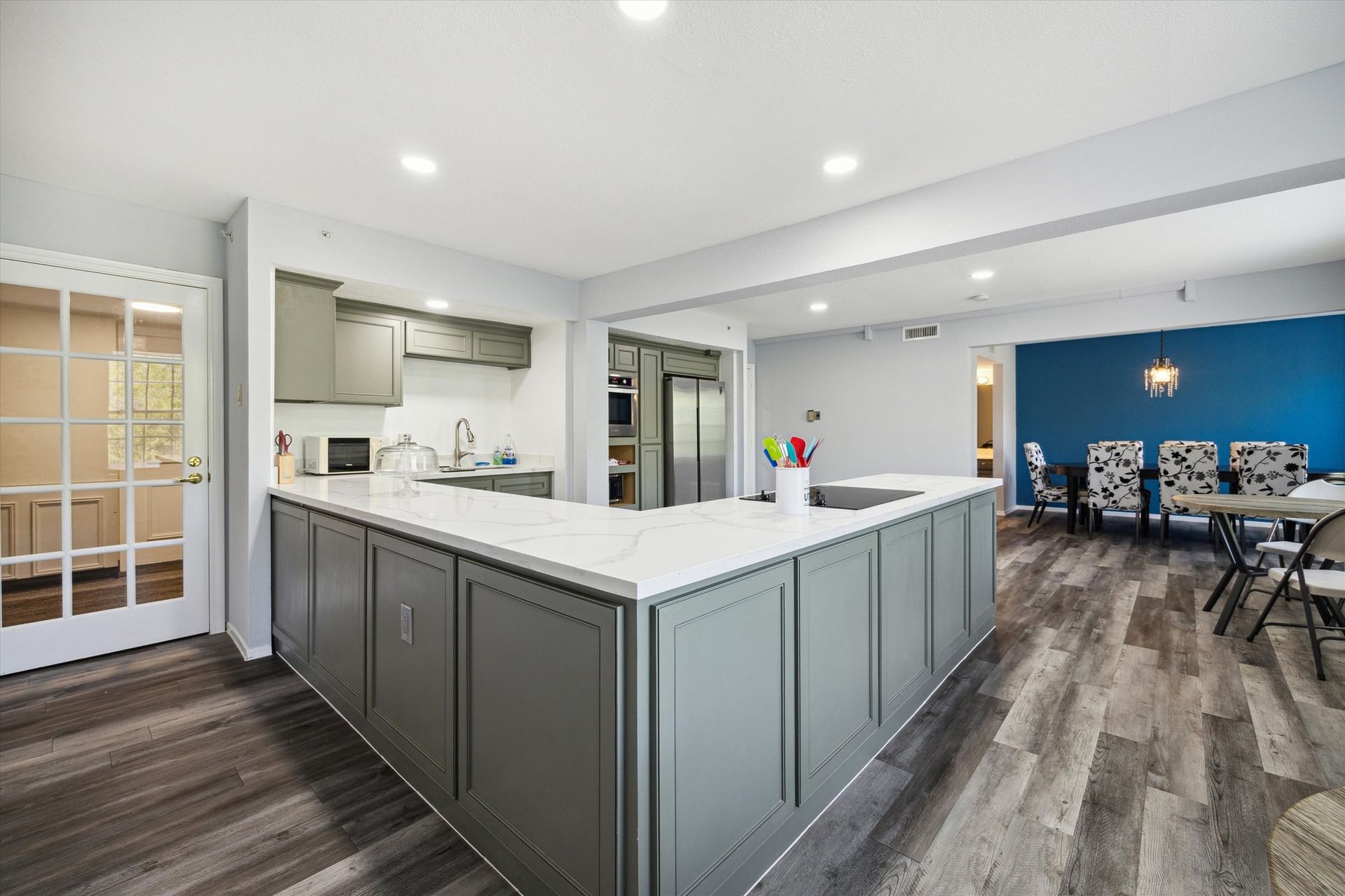 Modern kitchen with gray cabinetry, white countertops, and stainless steel appliances.