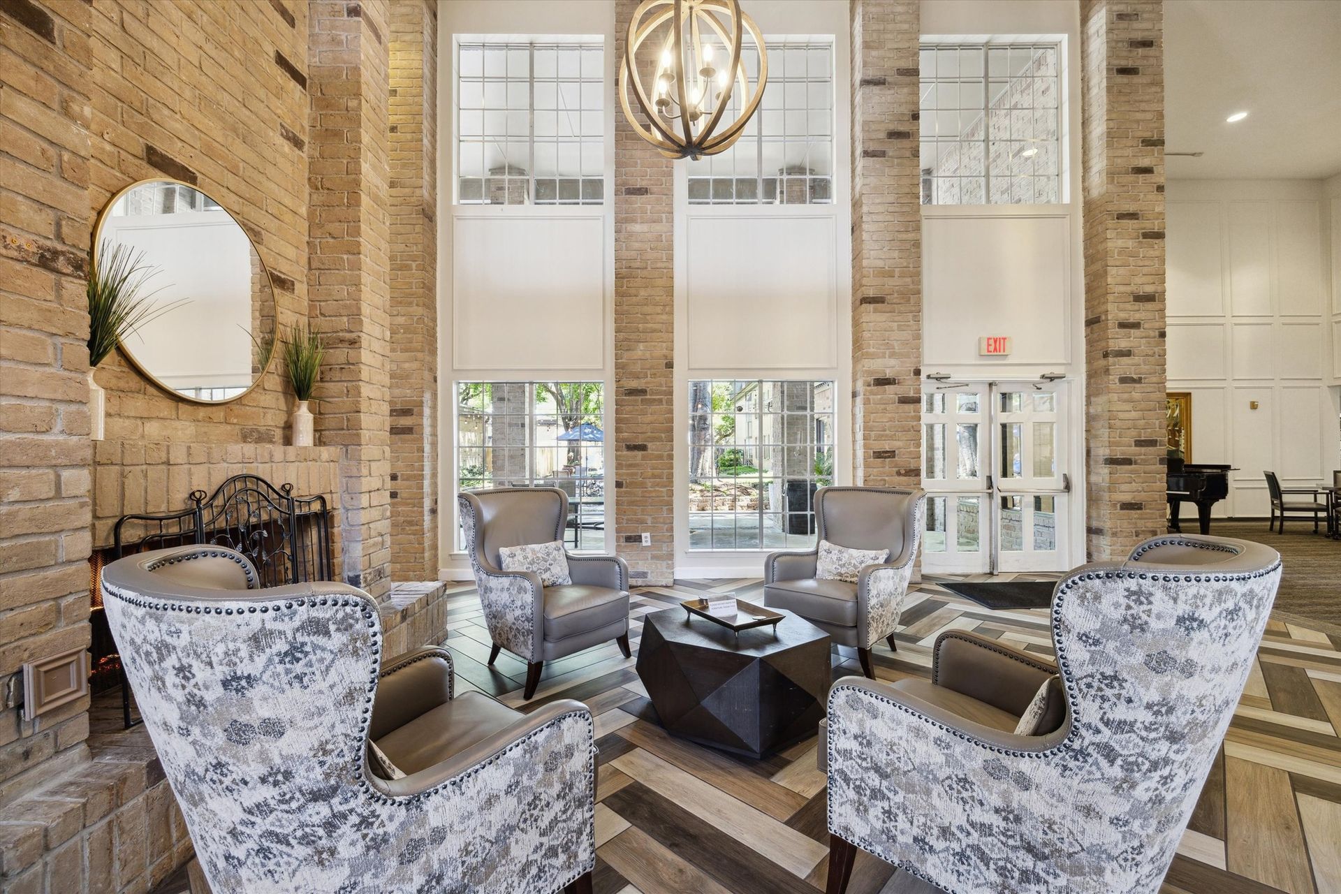 Lobby with seating area, exposed brick columns, large windows, chandelier, and a decorative fireplace.
