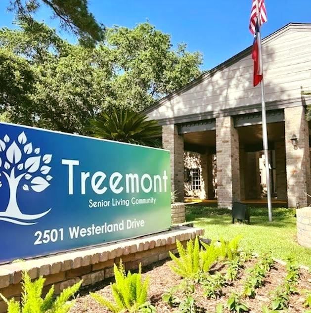 Treemont Senior Living Community sign, building with flag in the background, green and blue sign.