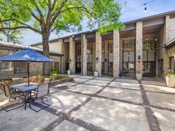 Exterior courtyard with patio furniture, brick flooring, and a building with large windows.