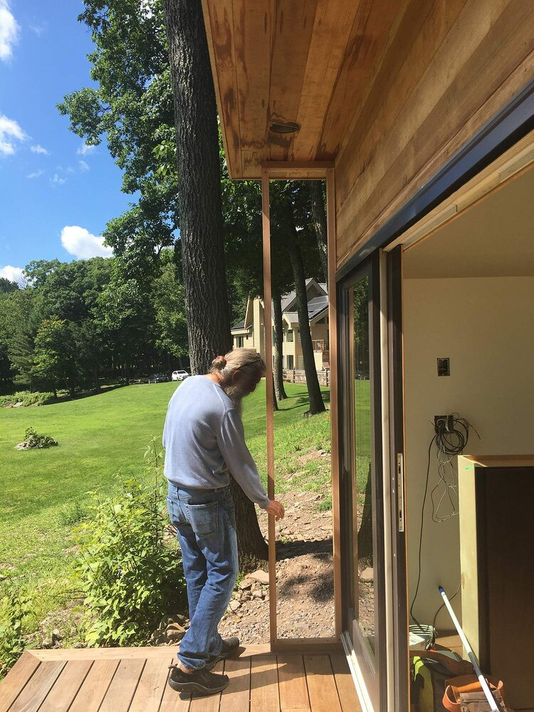 A man is standing on a deck next to a sliding glass door.