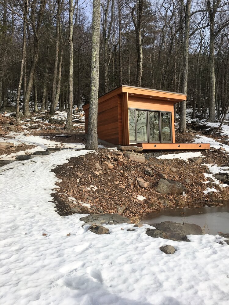 A small wooden house is sitting in the middle of a snowy forest.