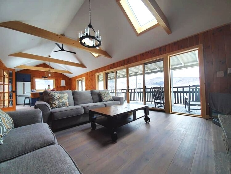 A living room with a couch , chair , coffee table and lots of windows.