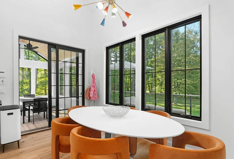 A dining room with a white table and orange chairs.