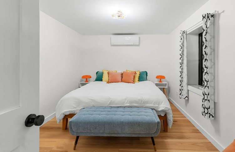 A bedroom with a large bed and a blue ottoman