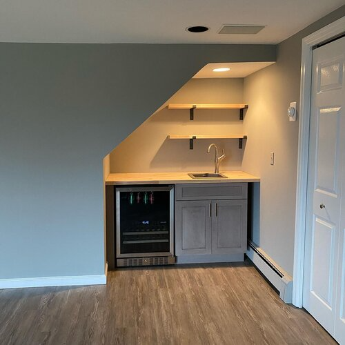 A kitchen with a sink and a refrigerator under the stairs