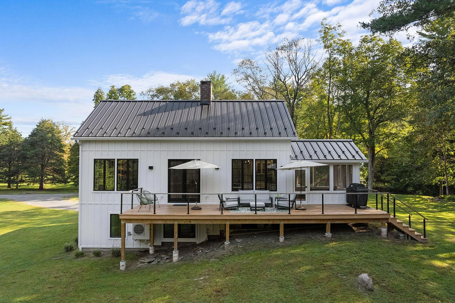 A white house with a large deck in the backyard.
