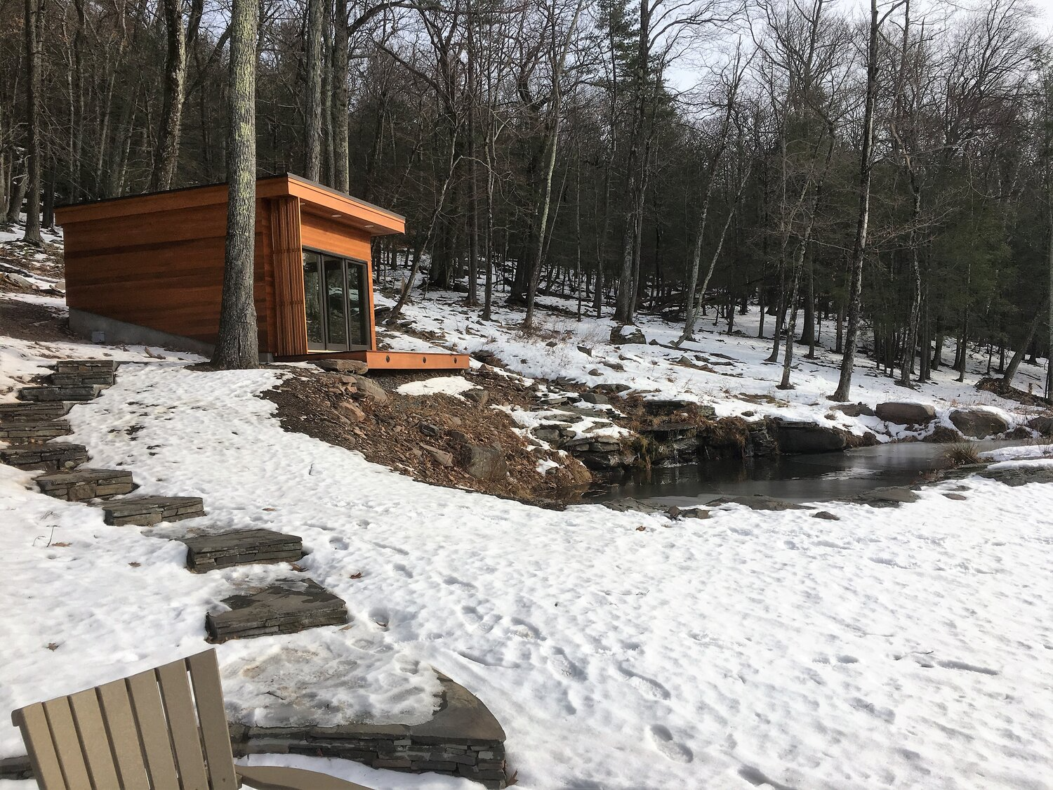 A wooden house is sitting in the middle of a snowy forest.