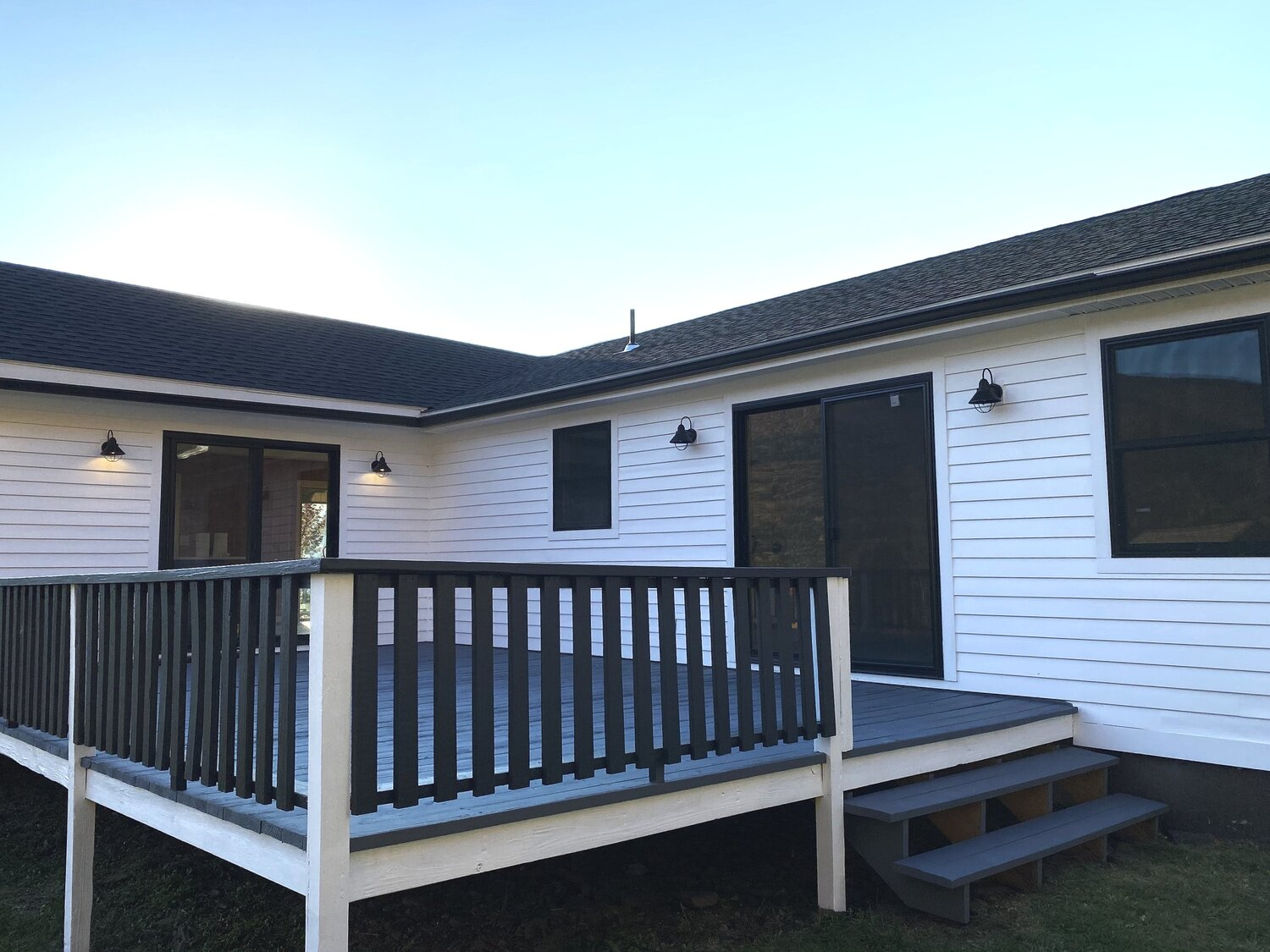 A white house with a deck and stairs in front of it.