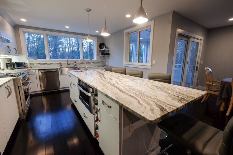 A kitchen with a large granite counter top and stainless steel appliances.