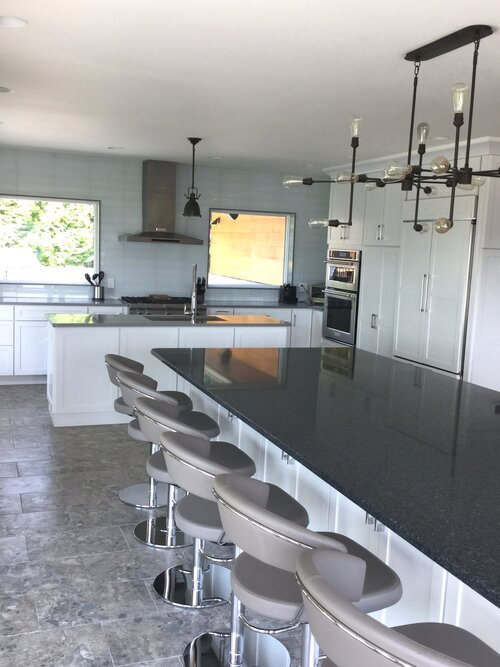 A kitchen with a long black counter top and stools
