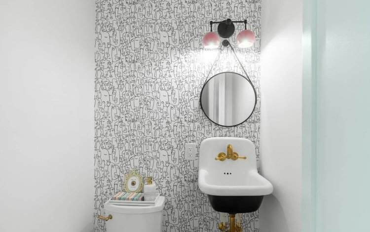 A bathroom with a toilet , sink and mirror.