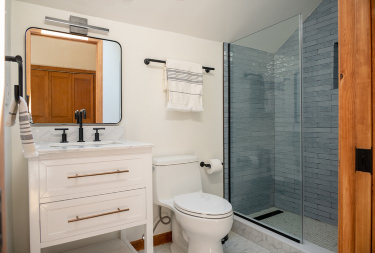 A bathroom with a toilet , sink , mirror and walk in shower.