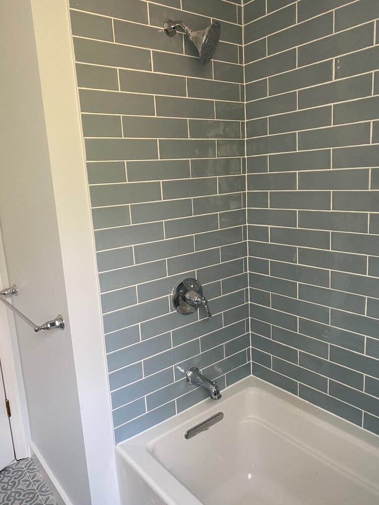 A bathroom with a bathtub and a shower with a brick wall