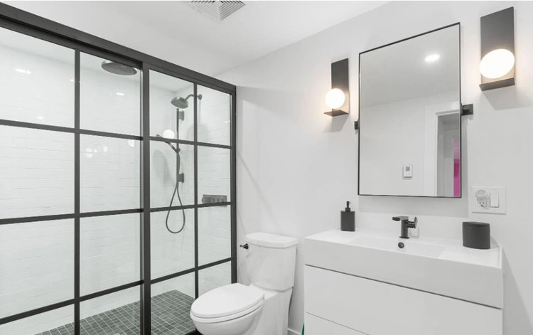 A bathroom with a toilet , sink , shower and mirror.