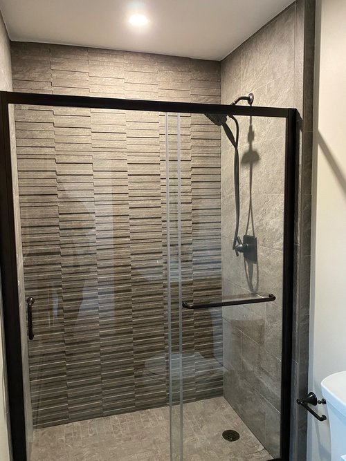 A bathroom with a sliding glass shower door and a shower head.